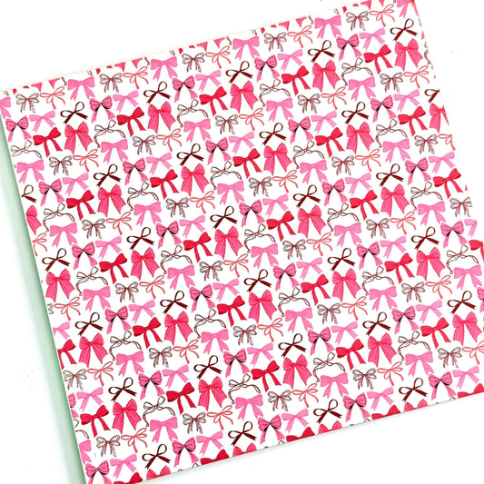 a repeating pattern of pink bows on a white acrylic background.