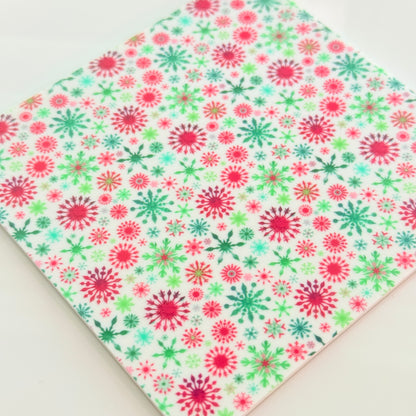 a square-shaped pattern with a repeating design of red and green snowflakes on a white background.