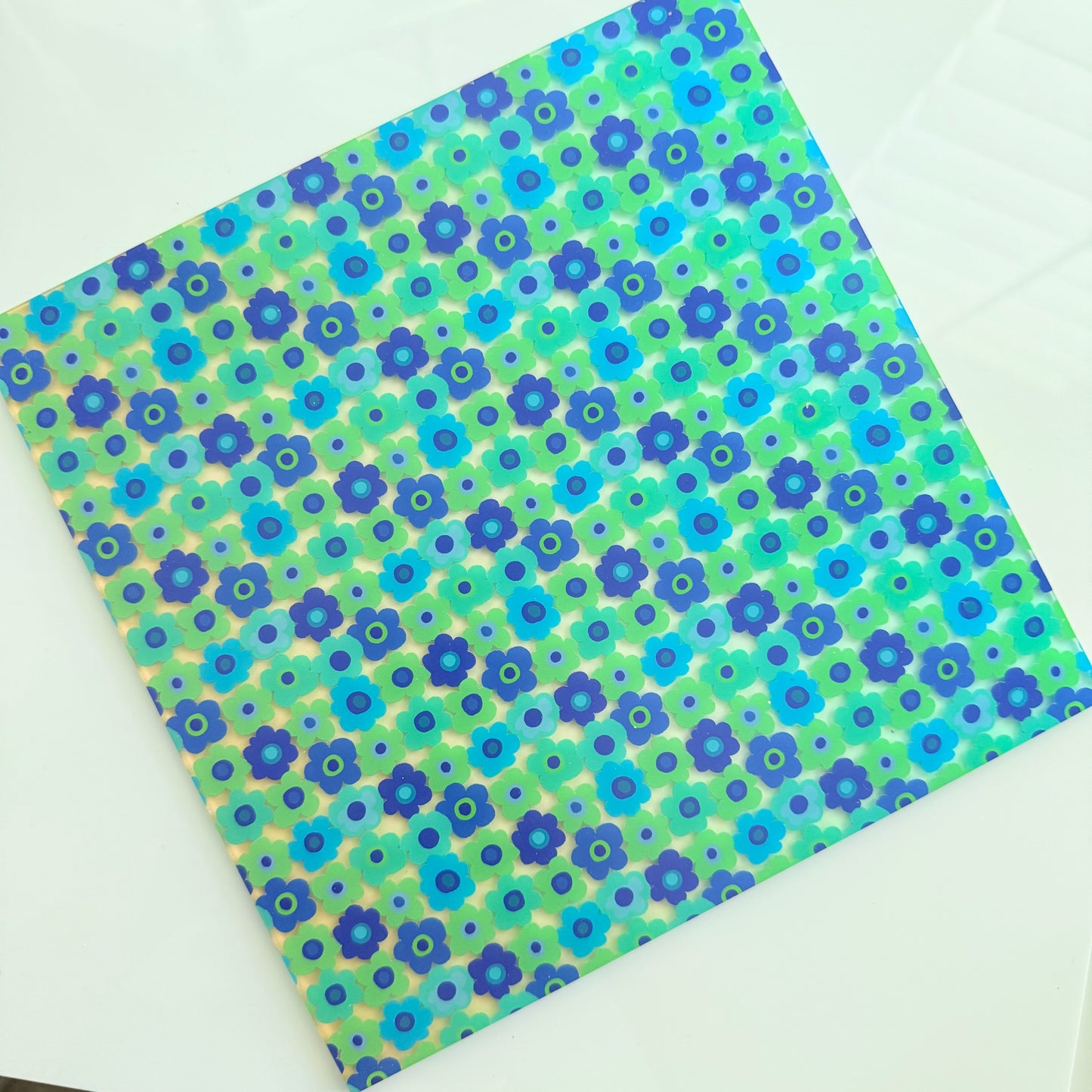 a square-shaped paper with a vibrant floral pattern in shades of blue and green.
