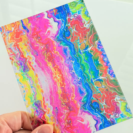 A hand is holding a colorful, abstract print with swirling patterns in various shades of pink, blue, green, and yellow.
