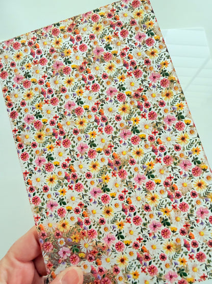 A hand is holding a piece of paper with a vibrant floral pattern on it.