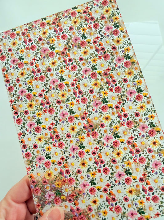 A hand is holding a piece of paper with a vibrant floral pattern on it.