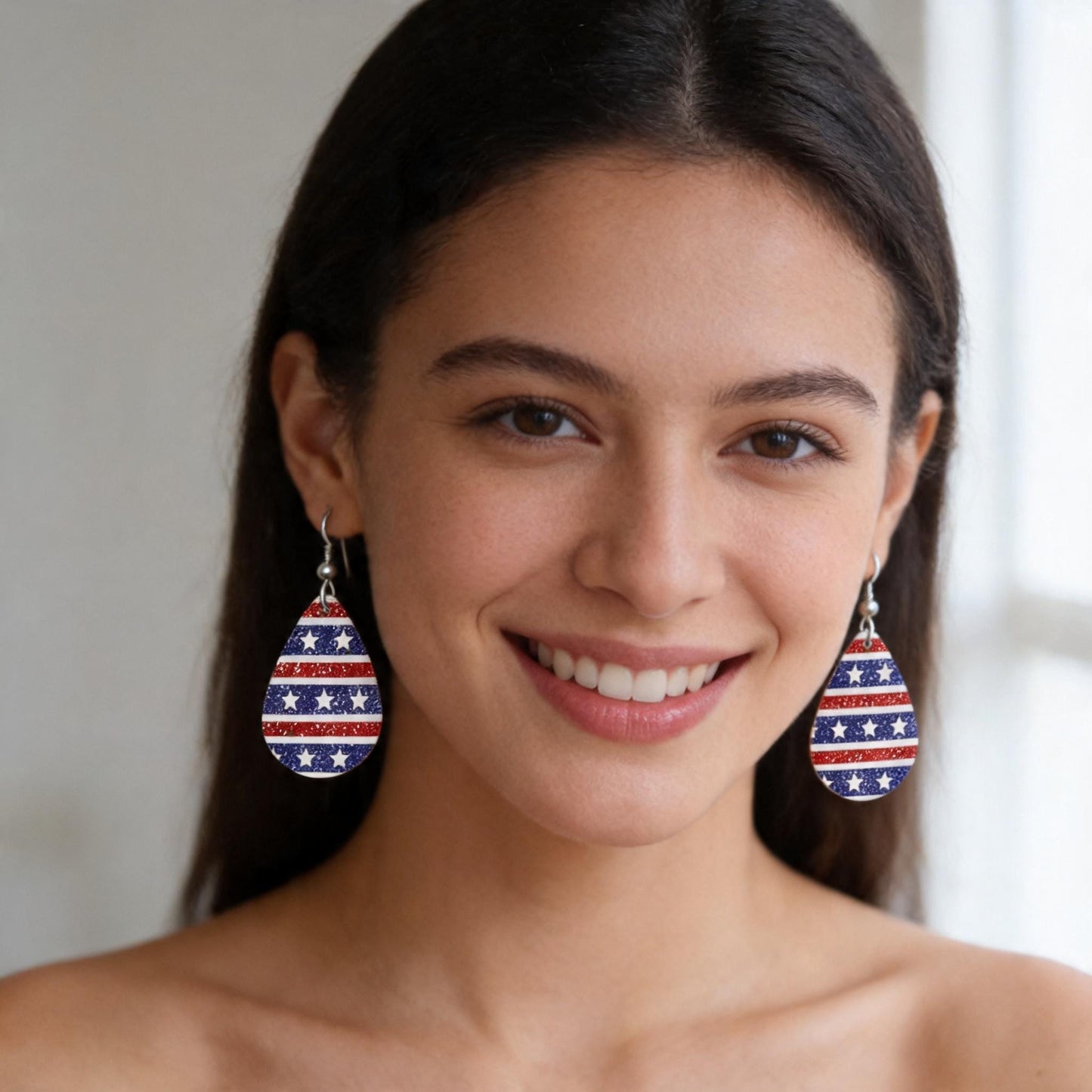 A woman with dark hair is smiling at the camera, wearing large earrings with a patriotic design.