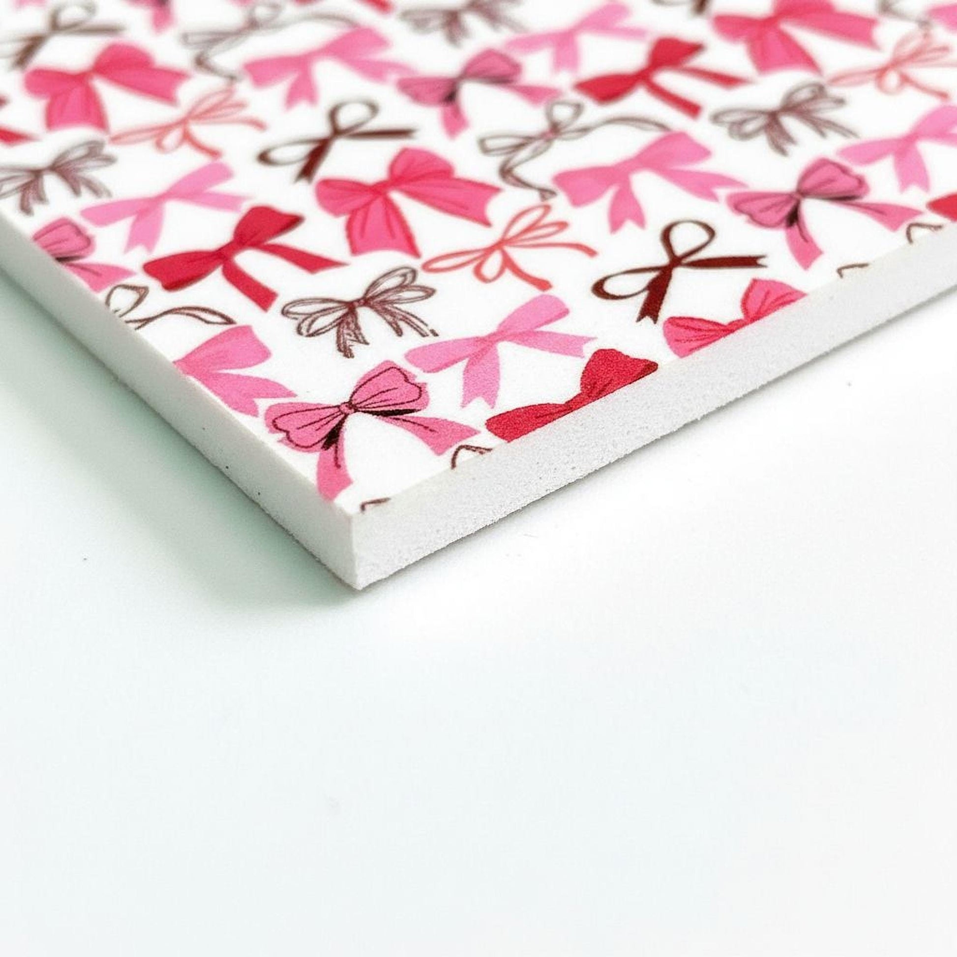 a close-up view of a white surface with a pattern of pink bows and brown bows.