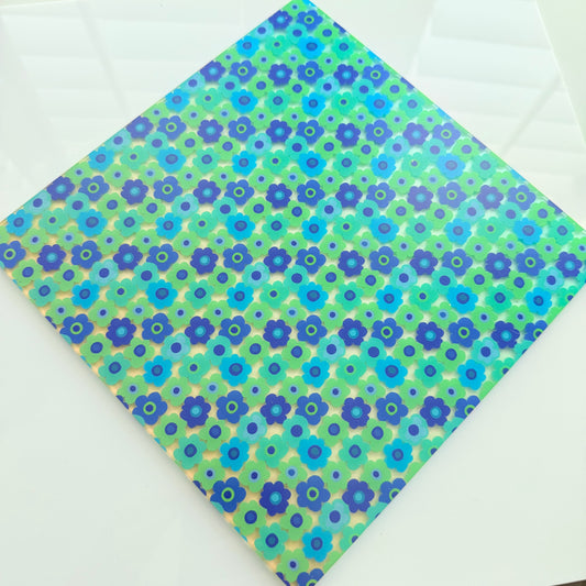 a diamond-shaped piece of paper with a vibrant floral pattern in shades of blue and green.